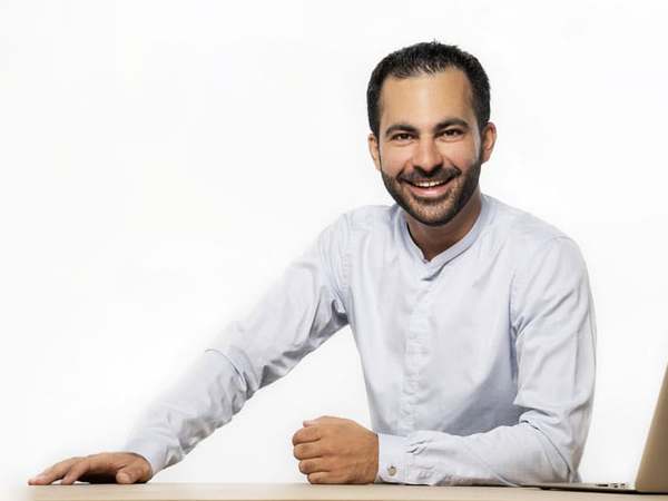 Hamed Farhadian smiling at his desk with a laptop