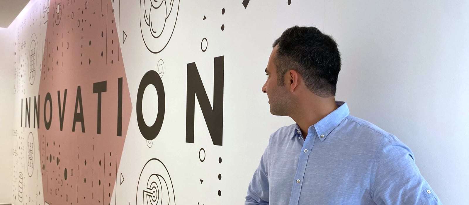 Hamed Farhadian in front of a wall with the word “Innovation”