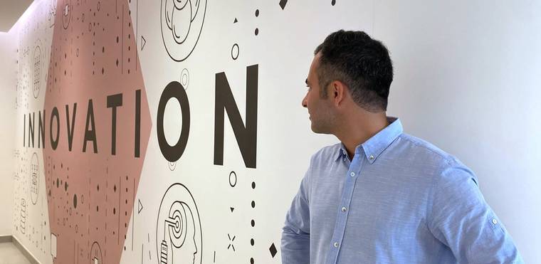 Hamed Farhadian in a light blue shirt, seen in profile in front of a wall with the large lettering “Innovation”.