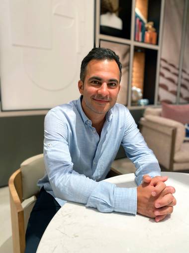 Hamed Farhadian smiling, sitting at a round table with his hands folded